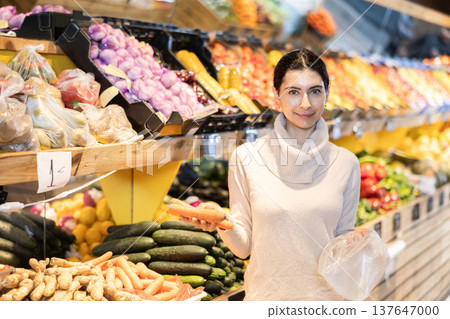 Young woman choosing carrots in vegetable shop 137647000