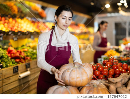 Woman seller offering pumpkins in a grocery store 137647012