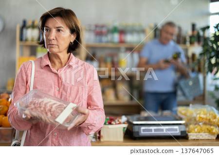 Woman chooses pork fillet, while her husband buys alcohol in supermarket 137647065