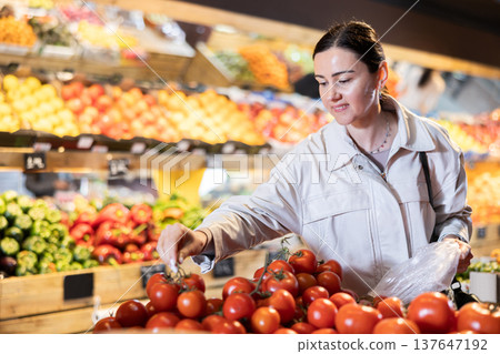 Middle-aged woman choosing tomatoes in grocery store 137647192