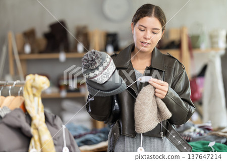 Young woman choosing hat in clothing store Young woman choosing hat in clothing store 137647214