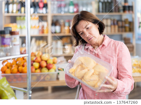 Mature woman choosing chicken in grocery store Mature woman choosing chicken in grocery store 137647260