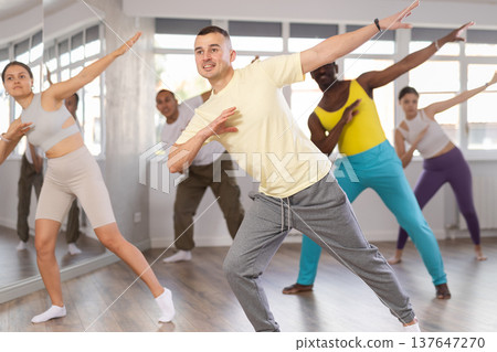 Young dancer rehearsing popping techniques during group workout Young dancer rehearsing popping techniques during group workout 137647270