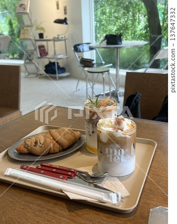 A delightful assortment of desserts displayed in a cozy cafe setting, featuring cakes, pastries, and sweet treats on elegant plates, creating a warm and inviting atmosphere. 137647332