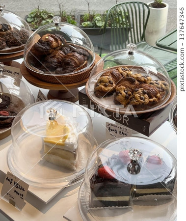 A delightful assortment of desserts displayed in a cozy cafe setting, featuring cakes, pastries, and sweet treats on elegant plates, creating a warm and inviting atmosphere. A delightful assortment of desserts displayed in a cozy cafe setting, featuring cakes, pastries, and sweet treats on elegant plates, creating a warm and inviting atmosphere. 137647346