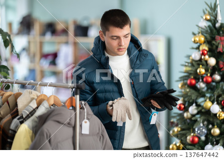 Young man choosing gloves in clothing store 137647442