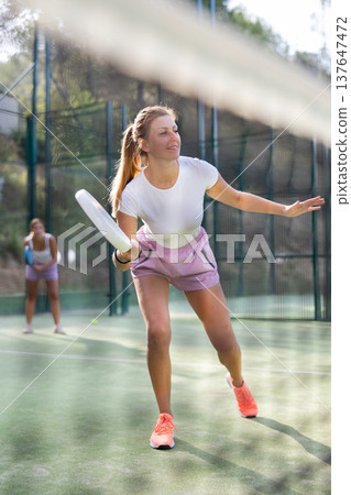 Woman playing padel tennis match during training on court Woman playing padel tennis match during training on court 137647472