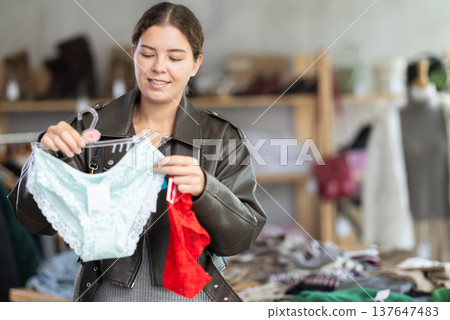 Cheerful young girl buyer choosing comfort panties in clothing store Cheerful young girl buyer choosing comfort panties in clothing store 137647483