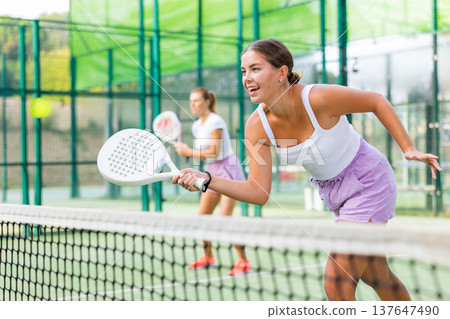 Young woman padel tennis player trains on the outdoor court 137647490