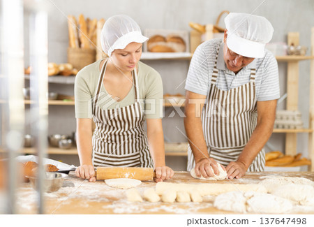 Man and woman bakers roll out dough with rolling pin Man and woman bakers roll out dough with rolling pin 137647498