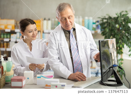 Male and female pharmacists checking prescription on computer Male and female pharmacists checking prescription on computer 137647513