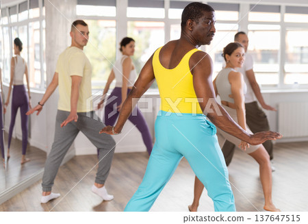 Enthusiastic black man energizing group during dance fitness class 137647515