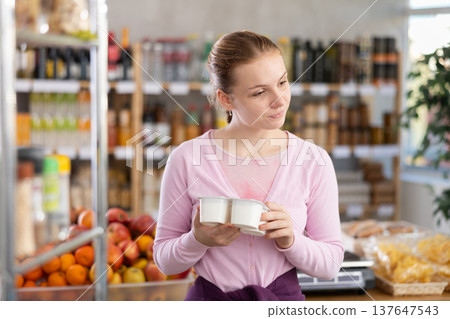 Woman chooses tasty yogurt to buy in the grocery department section of store 137647543