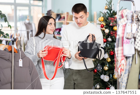 Couple in love choosing a handbag in a Christmas shop Couple in love choosing a handbag in a Christmas shop 137647551