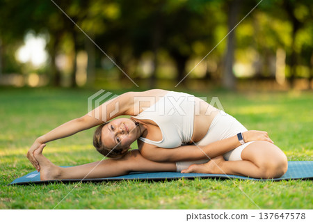 Young woman practicing yoga on green glade in summer park Young woman practicing yoga on green glade in summer park 137647578