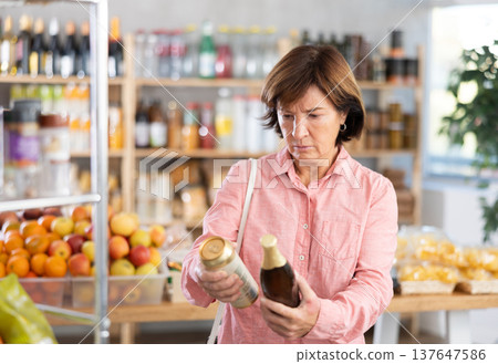 Choose alcohol in supermarket - woman chooses what beer to buy in alcohol section of store Choose alcohol in supermarket - woman chooses what beer to buy in alcohol section of store 137647586