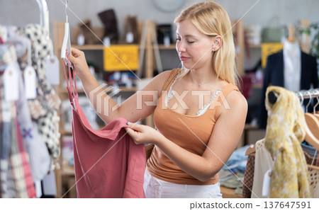 Fashionista girl near showcase examine goods, buying something clothing for summer. Fashionista girl near showcase examine goods, buying something clothing for summer. 137647591