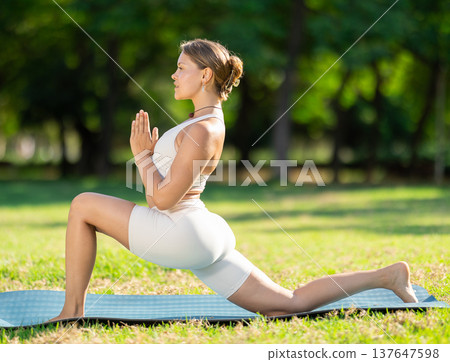 Young yogini performing Crescent Low Lunge Pose in summer park 137647598