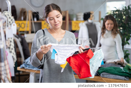 Cheerful young girl buyer choosing comfort panties in clothing store Cheerful young girl buyer choosing comfort panties in clothing store 137647651