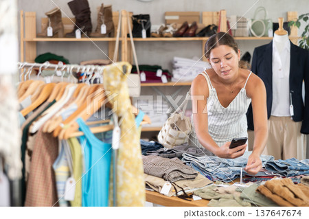 Young woman scanning qr code of trousers in clothing store Young woman scanning qr code of trousers in clothing store 137647674