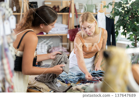 Two young women choosing trousers in store 137647689