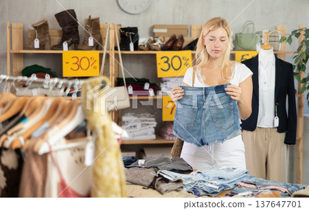 Young woman choosing denim shorts in clothing store 137647701