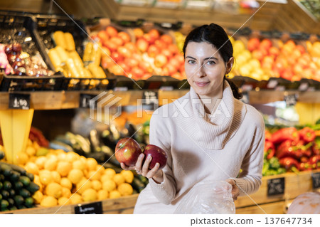 Young woman choosing apples in vegetable shop Young woman choosing apples in vegetable shop 137647734