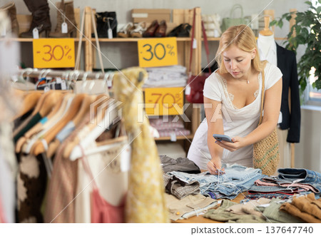 Woman scans barcode of pants with discounts on her phone Woman scans barcode of pants with discounts on her phone 137647740