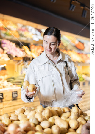 Middle-aged woman choosing potatoes in grocery store 137647746