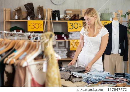 Woman chooses pants at discounts 137647772
