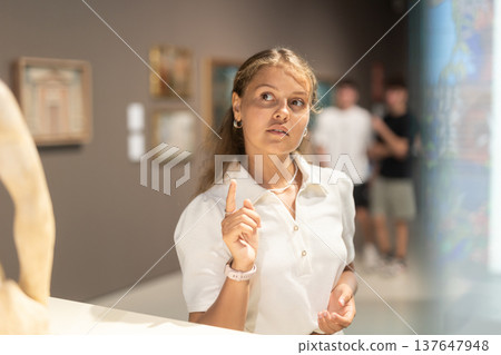 Girl walks around museum hall, view exhibition items 137647948