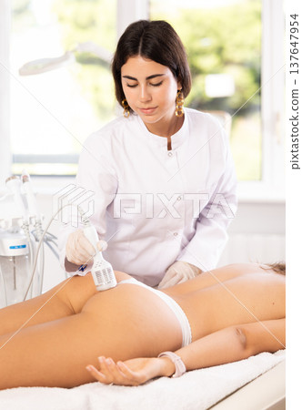 Cosmetologist performing hardware procedure on female buttocks using cooling attachment Cosmetologist performing hardware procedure on female buttocks using cooling attachment 137647954