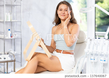 Young joyful woman examining her face after cosmetic procedure Young joyful woman examining her face after cosmetic procedure 137648067