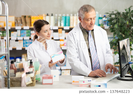 Male and female pharmacists looking for pills on computer Male and female pharmacists looking for pills on computer 137648223