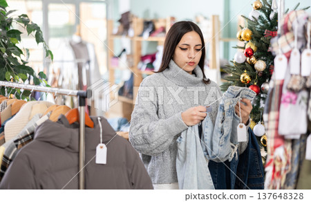 Girl shopper chooses jeans in clothing store before Christmas Girl shopper chooses jeans in clothing store before Christmas 137648328
