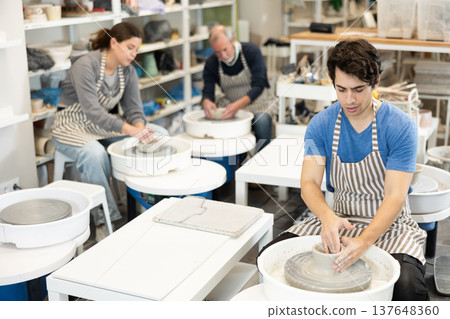 Guy potter works on potter wheel to create clay cup Guy potter works on potter wheel to create clay cup 137648360