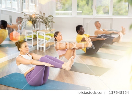 Asian woman balancing in Half Boat Pose at group yoga training Asian woman balancing in Half Boat Pose at group yoga training 137648364