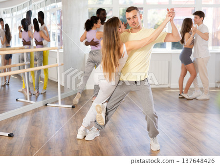 Young man and woman practicing salsa dance in pair in training hall Young man and woman practicing salsa dance in pair in training hall 137648426
