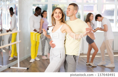 Smiling man and woman enjoying impassioned merengue at dance class 137648491