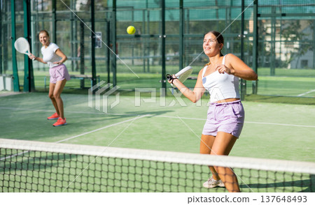 Girl playing padel tennis match during training on court Girl playing padel tennis match during training on court 137648493