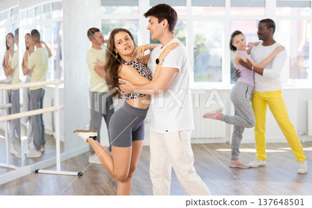 Happy pretty woman enjoying impassioned merengue with male partner in dance room during class. Social dancing concept Happy pretty woman enjoying impassioned merengue with male partner in dance room during class. Social dancing concept 137648501