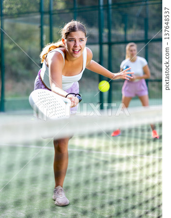 Active womans with enthusiasm playing padel on tennis court 137648537