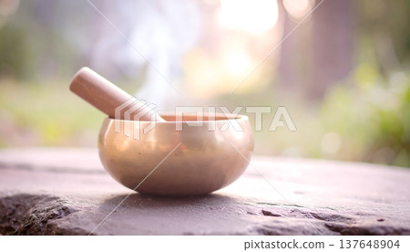 Singing bowl with wooden mallet on table in peaceful setting 137648904