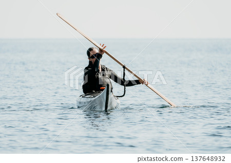 Kayaking Paddling Ocean - A kayaker paddles through the ocean, using a long oar to propel their boat. Kayaking Paddling Ocean - A kayaker paddles through the ocean, using a long oar to propel their boat. 137648932