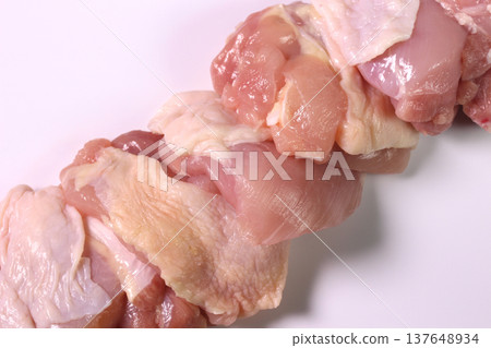 Close-up of a block of chicken thigh meat against a white background. Close-up of a block of chicken thigh meat against a white background. 137648934
