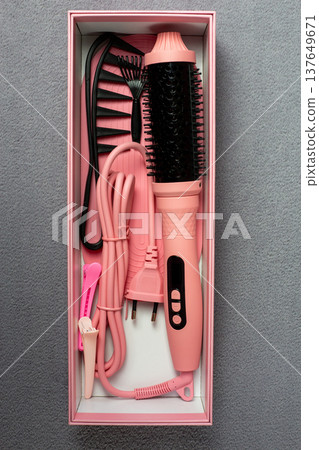 Complete pink electric hair styling kit with multi styler brush, comb, and clips. All essentials for perfect hairstyle in one box on grey background. Ideal for daily beauty routine Complete pink electric hair styling kit with multi styler brush, comb, and clips. All essentials for perfect hairstyle in one box on grey background. Ideal for daily beauty routine 137649671