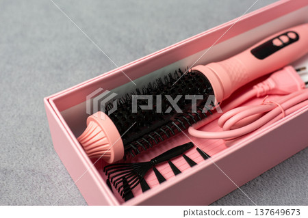 Ideal pink electric multi-styler for any hairstyle. Cylindrical brush with comb and clips on neutral background. Achieve curls, volume, or sleek straight looks effortlessly Ideal pink electric multi-styler for any hairstyle. Cylindrical brush with comb and clips on neutral background. Achieve curls, volume, or sleek straight looks effortlessly 137649673
