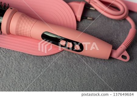 Close-up of pink electric hair styler handle featuring intuitive buttons and temperature display. Smart technology for precise heat control. Achieve perfect curls without damage Close-up of pink electric hair styler handle featuring intuitive buttons and temperature display. Smart technology for precise heat control. Achieve perfect curls without damage 137649684
