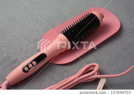 Premium pink electric hair styler displayed on elegant mat. High quality beauty tool exudes luxury and sophistication. Perfect for discerning women who value excellence in hair care 137649703