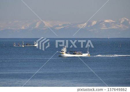 A photograph of fishing boats coming and going in Funka Bay off the coast of Yakumo Town, Hokkaido, in early spring. A photograph of fishing boats coming and going in Funka Bay off the coast of Yakumo Town, Hokkaido, in early spring. 137649862